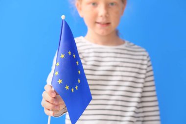 Mavi arka planda Avrupa Birliği bayrağı taşıyan küçük kız, yakın plan.