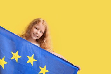 Sarı arka planda Avrupa Birliği bayrağı taşıyan küçük kız