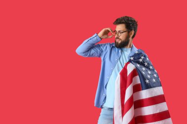 Kırmızı arka planda Amerikan bayrağı olan yakışıklı sakallı adam.