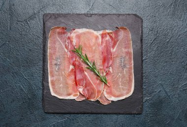 Lezzetli jambon dilimleri ve koyu renk arka planda biberiye içeren tahta.