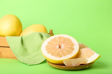 Yeşil arka planda zeytinli, dilimli ve sepetli meyve tabağı.