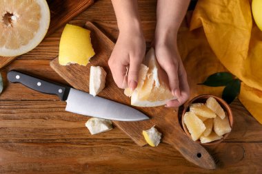 Ahşap zemin üzerinde taze meyve ve bıçak parçasıyla kadın elleri.