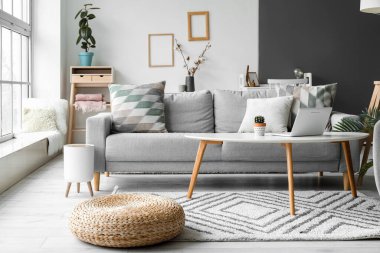 Gri kanepeli, masalı ve dizüstü bilgisayarlı aydınlık oturma odasının içi.