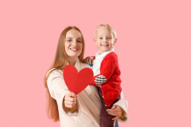 Güzel bir kadın ve pembe arka planda Sevgililer Günü için kağıt kalpli küçük oğlu.