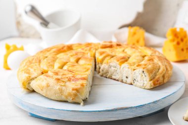 Beyaz masanın üzerinde lezzetli peynirli turta parçaları olan tahta.