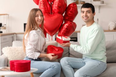 Sevgililer Günü 'nde mutfakta hediyelerle birbirlerini selamlayan genç bir çift.