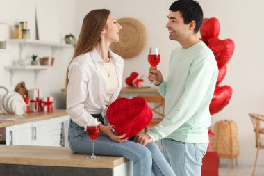 Sevgililer Günü 'nde mutfakta hediye ve şarap taşıyan genç çift.