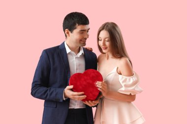 Pembe arka planda hediyeye aşık genç bir çift. Sevgililer Günü kutlaması