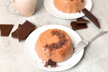 Lezzetli puding, çikolata ve gri masada bir fincan süt.