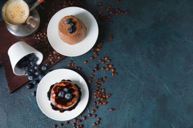 Lezzetli çikolatalı puding tabaklar, ters çevrilmiş bir fincan yabanmersini kahve çekirdekleri ve kapuçino.