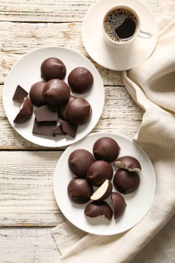 Çikolatalı tatlı kuş sütlü tabaklar ve beyaz ahşap arka planda bir fincan kahve.