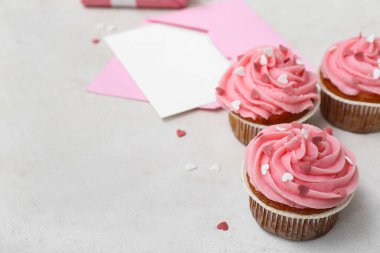 Beyaz arkaplanda Sevgililer Günü için lezzetli kekler ve zarf, yakın plan.