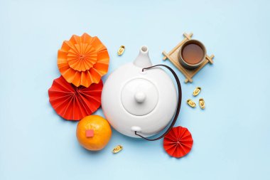 Mavi arka planda fincan, mandalina ve Çin sembolleri olan çaydanlık. Yeni yıl kutlaması