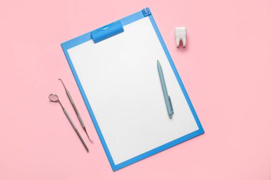 Pembe arka planda kalem, plastik diş ve diş aletleri bulunan pano