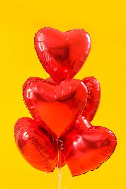 Sarı arkaplanda Sevgililer Günü için kalp şeklinde balonlar.