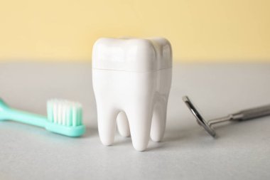 Sarı arka planda diş fırçası ve diş fırçası ile plastik diş, yakın plan