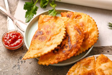 Lezzetli chebureks tabağı ve masada sos.