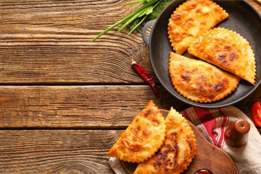 Ahşap arka planda lezzetli çizburgerleri olan kızartma tavası ve yemek.