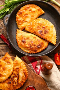 Ahşap arka planda lezzetli çizburgerleri olan kızartma tavası ve yemek.