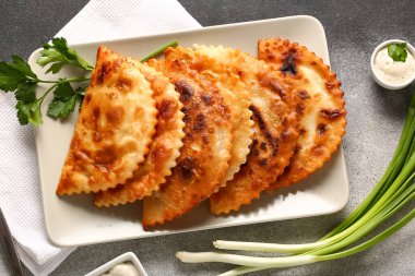 Lezzetli chebureks, maydanoz, soğan ve soslu grunge soslu tabak.