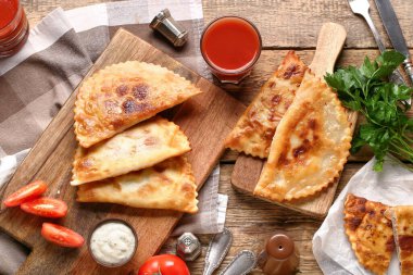 Tahta kesme tahtaları lezzetli chebureks, maydanoz, domates suyu ve ahşap zemin üzerinde sos