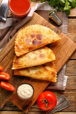 Ahşap zemin üzerinde lezzetli chebureks, sos ve domates suyu ile kesme tahtası