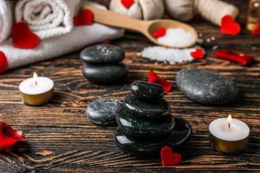 Koyu ahşap masada yanan mumlarla kaplıca taşları, yakın plan. Sevgililer Günü kutlaması