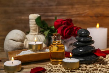 Yanan mumlarla kaplıca taşları ve ahşap masada güller, yakın plan. Sevgililer Günü kutlaması