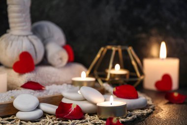 Gül yapraklı spa taşları ve karanlık masa üzerinde mumlar, yakın plan. Sevgililer Günü kutlaması