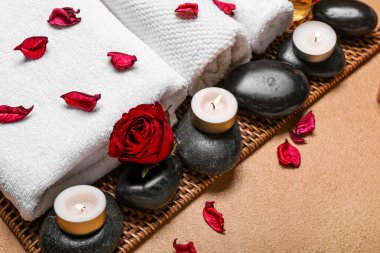 Sevgililer Günü için bej arka planda taşlar, gül yaprakları ve mumlarla spa kompozisyonu