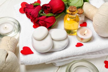 Beyaz ahşap arka planda taşlar, güller ve mumlarla Sevgililer Günü için spa kompozisyonu, yakın plan.