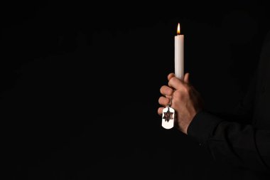 Elinde mum ve künyesi olan Yahudi bir adamın elleri. Soykırım kurbanlarını onurlandırıyor.