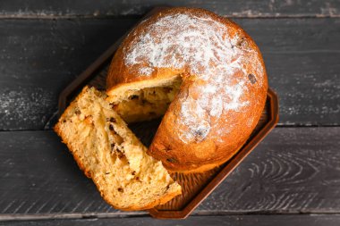 Siyah ahşap arka planda kesilmiş Panettone tahtası