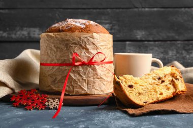 Koyu renkli masada fincanlı panettone ve kar taneleri, yakın plan.