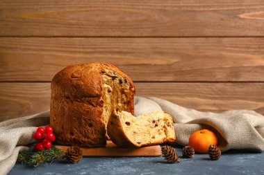 Panettone, köknar konileri ve ahşap duvarın yanındaki masada mandalinalar.