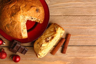 Kesik Panettone, çikolata, tarçın ve Noel topları ile ahşap, üst görünüm