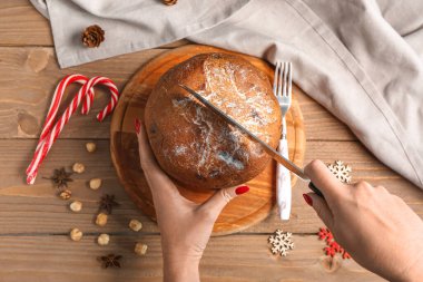 Ahşap masada nefis Panettone kesen kadın, üst manzara.
