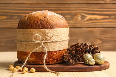 Panettone, köknar kozalakları ve tahta masada Noel topları.