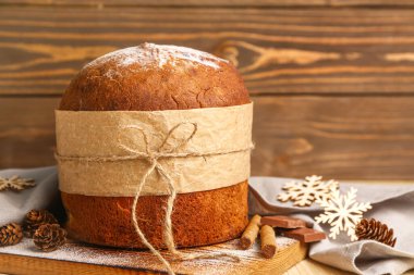 Panettone, tarçın ve köknar kozalakları ahşap masada, yakın plan.
