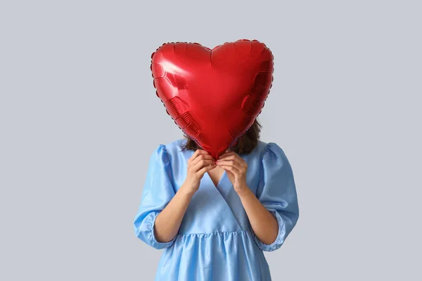 Young woman with heart shaped balloon on grey background. Valentine\'s Day celebration