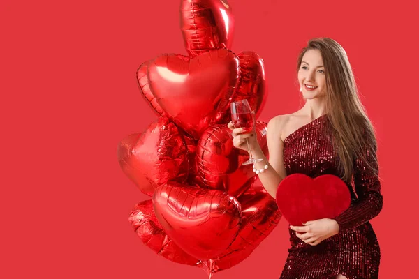 年轻的女人带着酒杯 礼物和红色背景的气球 情人节庆祝活动 — 图库照片