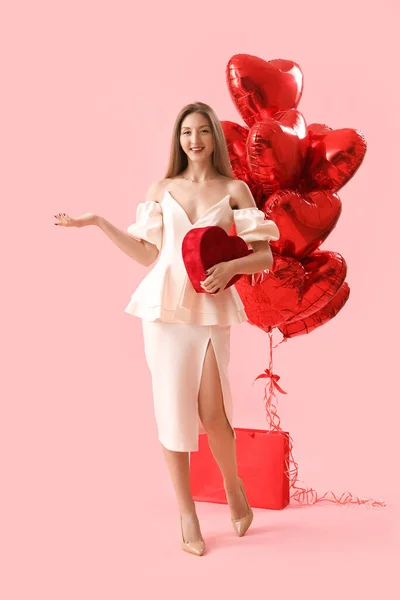 带着礼物和粉色背景气球的年轻女人情人节庆祝活动 — 图库照片