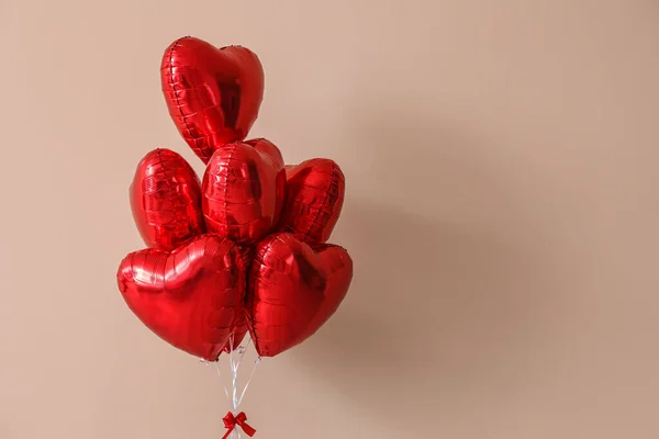 Heart-shaped balloons for Valentine\'s Day near beige wall