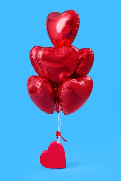 Gift with heart-shaped balloons for Valentine\'s Day on blue background