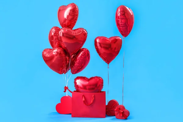 Shopping bag with heart-shaped balloons and gifts for Valentine's Day on blue background