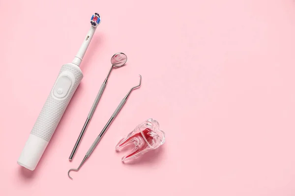 Plastic tooth with dental tools and electric brush on pink background