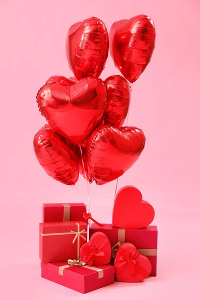 Gifts with heart-shaped balloons for Valentine\'s Day on pink background