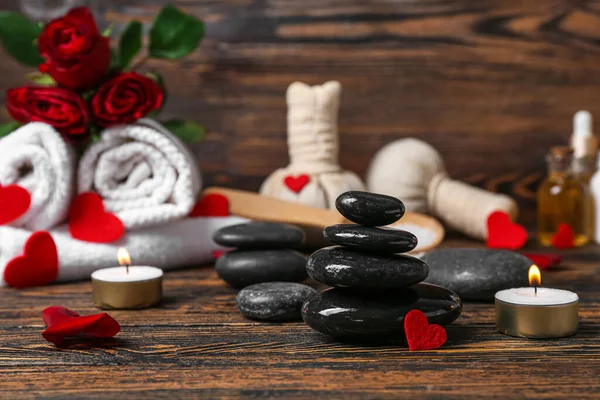 Spa stones with burning candles on dark wooden table, closeup. Valentine\'s Day celebration