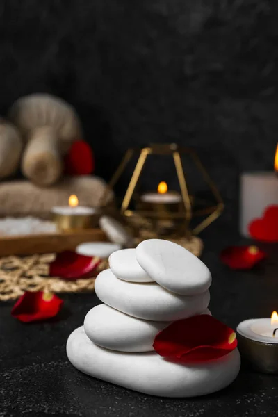 Spa stones with rose petals on dark table, closeup. Valentine\'s Day celebration