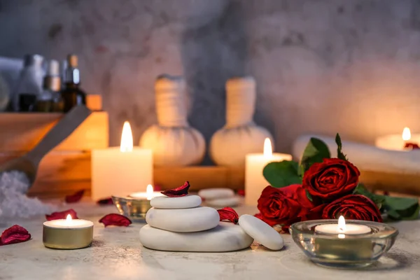 Spa stones with roses and candles on table, closeup. Valentine\'s Day celebration